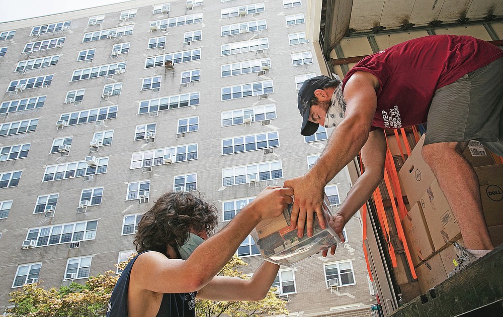 Jakob Howell, left, and Matt Brown load boxes belonging to Joyce and Anil Lilly into a moving truck, Tuesday, July 21, 2020, in The Bronx borough of New York. The Lilly's are leaving their 14th floor apartment and are moving to a town an hour's drive north, amid the coronavirus pandemic. (AP Photo/Mark Lennihan)