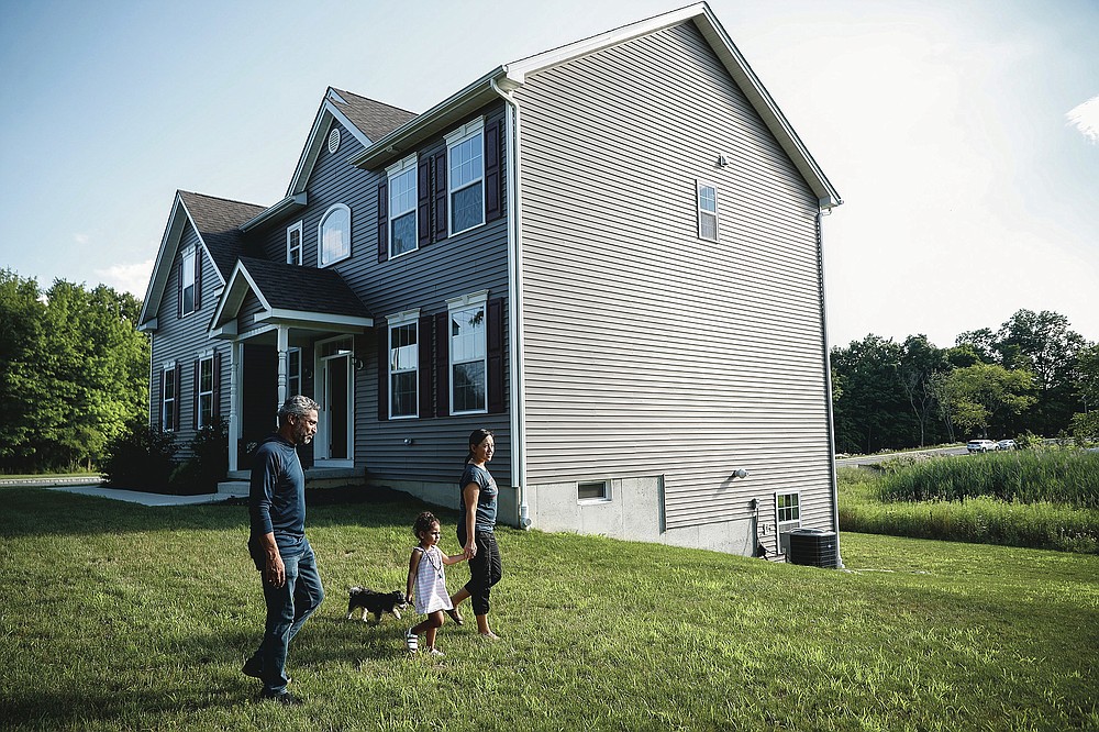Joyce Lilly, right, holds her granddaughter Paige's hand alongside her husband, Anil, and dog Max at their new home, Tuesday, July 21, 2020, in Washingtonville, N.Y. New Yorkers anxious after weathering the worst of the coronavirus pandemic are fueling a boom in home sales and rentals around the picturesque towns and wooded hills to the north. Real estate brokers and agents describe a red-hot market recently, with many house hunters able to work from home. (AP Photo/John Minchillo)