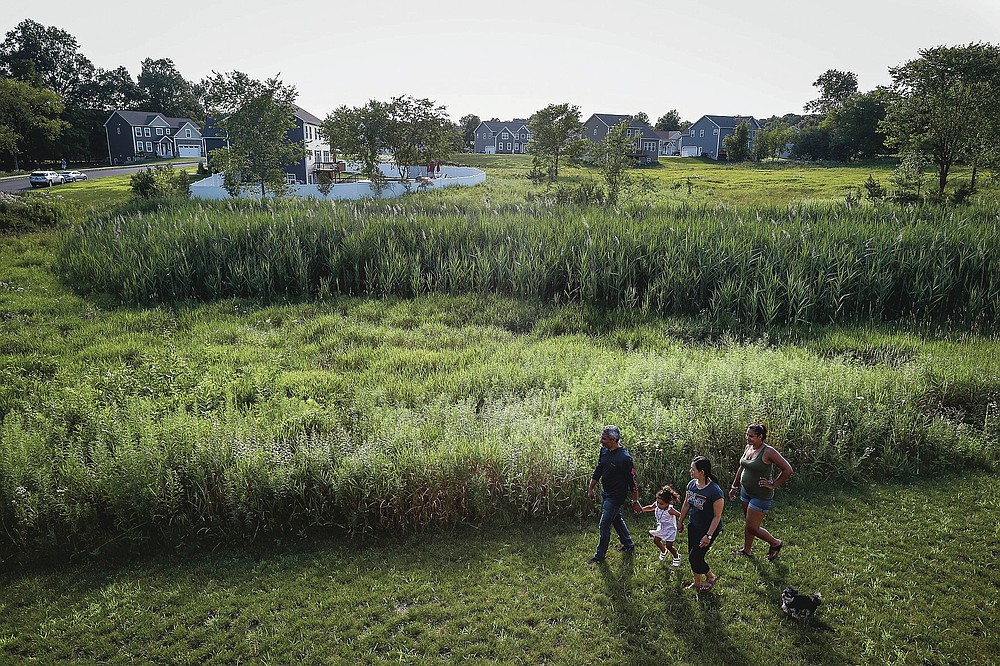 From left, Anil Lilly, granddaughter Paige, wife Joyce, and daughter Britney tour their new home, along with their dog Max, Tuesday, July 21, 2020, in Washingtonville, N.Y. New Yorkers anxious after weathering the worst of the coronavirus pandemic are fueling a boom in home sales and rentals around the picturesque towns and wooded hills to the north. Real estate brokers and agents describe a red-hot market recently, with many house hunters able to work from home. (AP Photo/John Minchillo)