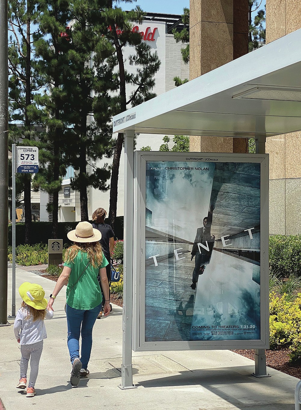In this June 27, 2020 photo, people walk by a poster promoting the long-awaited Christopher Nolan film "Tenet," in Los Angeles. The film, which had hoped to herald Hollywood’s return to big theatrical releases, has yet again postponed its release due to the ongoing coronavirus pandemic. Warner Bros. said Monday, July 20, that “Tenet” will not make its August 12 release date. And unlike previous delays, the studio this time didn’t announce a new target for the release of Nolan’s much-anticipated $200 million thriller. (AP Photo/Anthony McCartney)