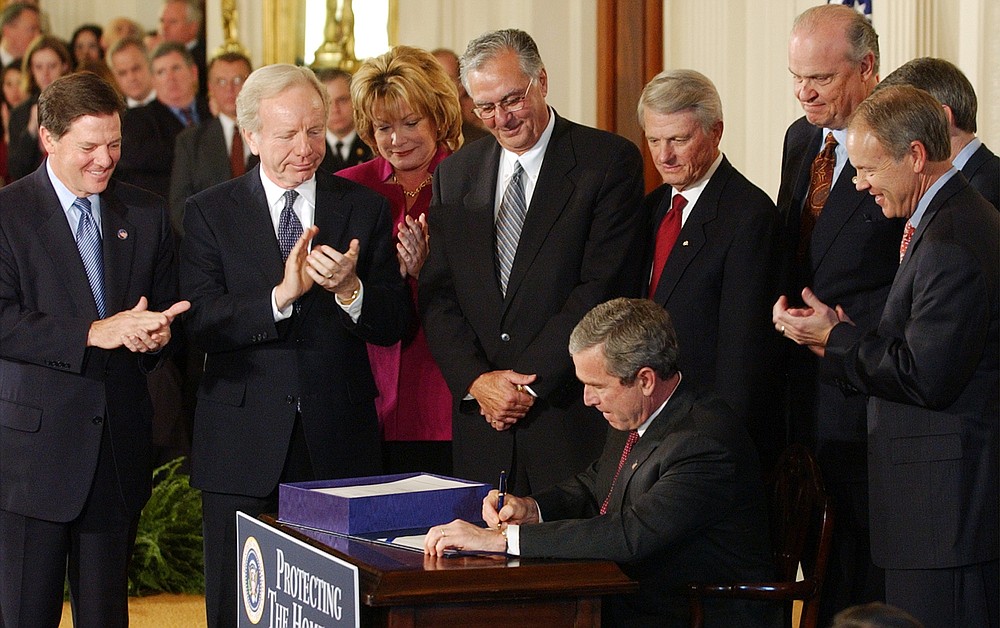 FILE - In this Monday, Nov. 25, 2002 file photo, President Geroge W. Bush signs legislation creating the Department of Homeland Security, during a ceremony at the White House in Washington. On Friday, July 24, 2020, The Associated Press reported on stories circulating online incorrectly asserting that former President Barack Obama signed the law authorizing federal agents to “snatch” protesters off the streets in Portland, Ore. The White House says 40 U.S Code 1315, under the Homeland Security Act of 2002, gives the Trump administration the authority to send armed federal agents to confront protesters in Portland. It was signed into law by President George W. Bush. (AP Photo/Susan Walsh)