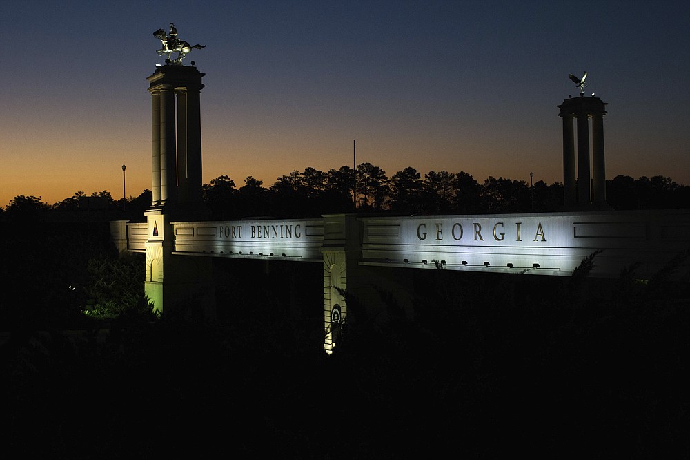 FILE - In this Oct. 16, 2015, file photo a bridge marks the entrance to the U.S. Army's Fort Benning as the sun rises in Columbus, Ga. The Senate on Thursday, July 23, 2020, joined the House in defying a veto threat from President Donald Trump to approve defense legislation that would remove the names of Confederate officers from American military bases such as Fort Bragg and Fort Benning. (AP Photo/Branden Camp, File)