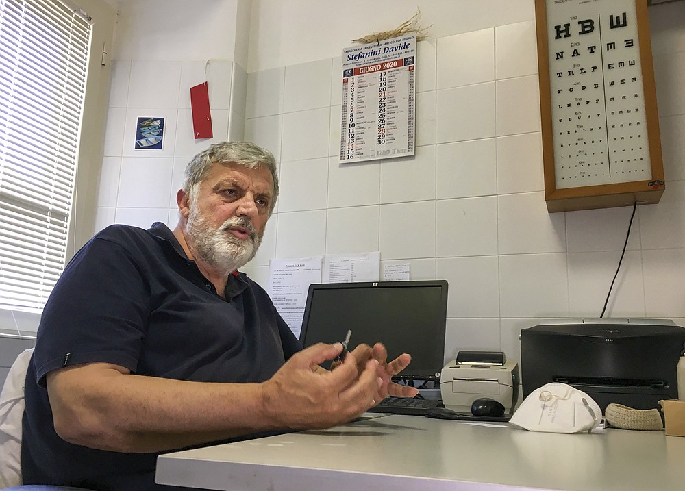 Armando Schiaffino, a native son and the island’s doctor for some 40 years now, talks with the Associated Press during an interview in his studio at the Giglio Island, Italy, Tuesday, June 23, 2020. Italian scientist Paola Muti was stranded on the tiny island where mainlanders sick with COVID-19 came ashore but no islanders apparently took ill. So she decided to do a scientific study to find out why. (AP Photo/Paolo Santalucia)