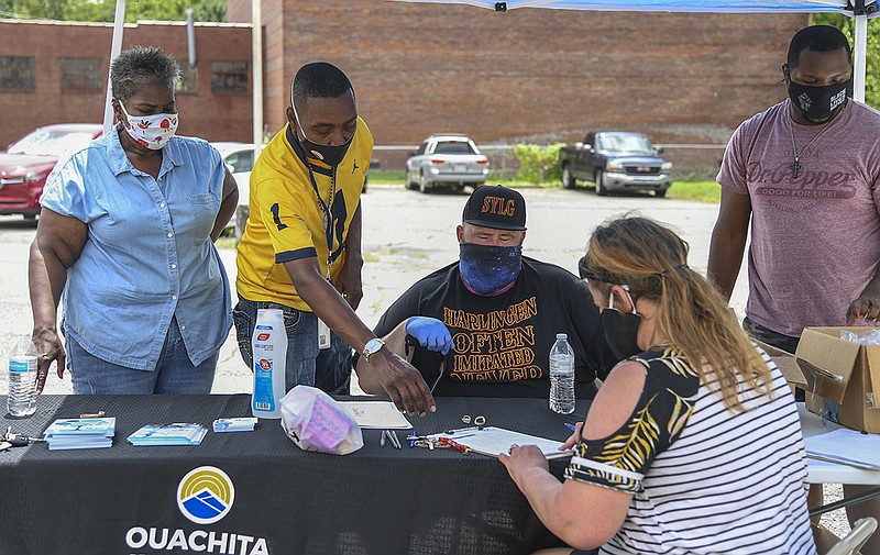 From left, Janice Davis, founder of The Giving Team, Boyce Mitchell and Josh Kassaw, both with Ouachita Behavioral Health and Wellness, and Tristian Traylor with The Giving Team help an attendee at the inaugural "Food for Thought" event Saturday at the intersection of Malvern Avenue and Church Street. - Photo by Grace Brown of The Sentinel-Record