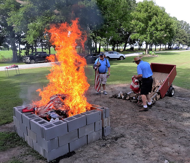 Photo submitted Jimmy "JJ" Johns, left, and Fay Ryan, members of American Legion Post 341 in Bella Vista, wait their turn to place American flags on a fire during a flag retirement ceremony at the home of Tommy and Jean Meacham, in Pea Ridge July 25.