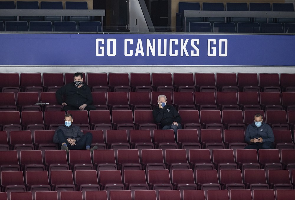 Vancouver Canucks general manager Jim Benning, top left, watches from the stands during the NHL hockey team's training camp in Vancouver, British Columbia, Saturday, July 25, 2020. (Darryl Dyck/The Canadian Press via AP)