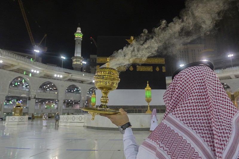 A man burns incense as the area around the Kaaba, the square structure in the Great Mosque, toward which believers turn when praying, is prepared for pilgrims, in Mecca, Saudi Arabia, late Sunday, July 26, 2020. Anywhere from 1,000 to 10,000 pilgrims will be allowed to perform the annual hajj pilgrimage this year due to the virus pandemic. (Saudi Ministry of Media via AP)
