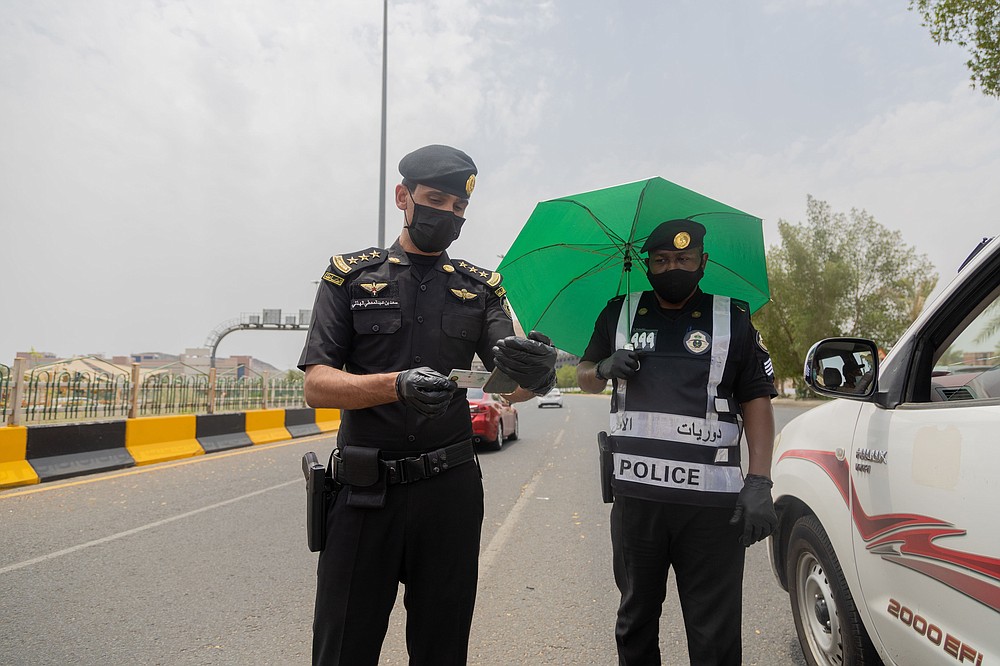In this July 26, 2020, photo, Saudi security officers check the identification cards of people entering Mecca ahead of the annual hajj pilgrimage. The Islamic pilgrimage has been dramatically downsized this year with only a few thousand residents of Saudi Arabia permitted to take part due to concerns over the coronavirus. (Saudi Ministry of Media)