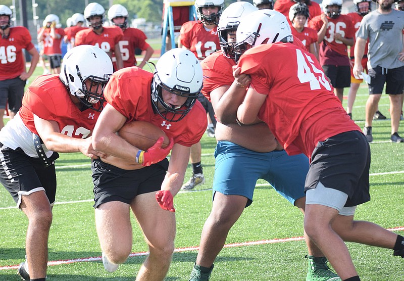 RICK PECK/SPECIAL TO MCDONALD COUNTY PRESS McDonald County running back Bailey Lewis runs through a hole during a workout on July 23 at MCHS.