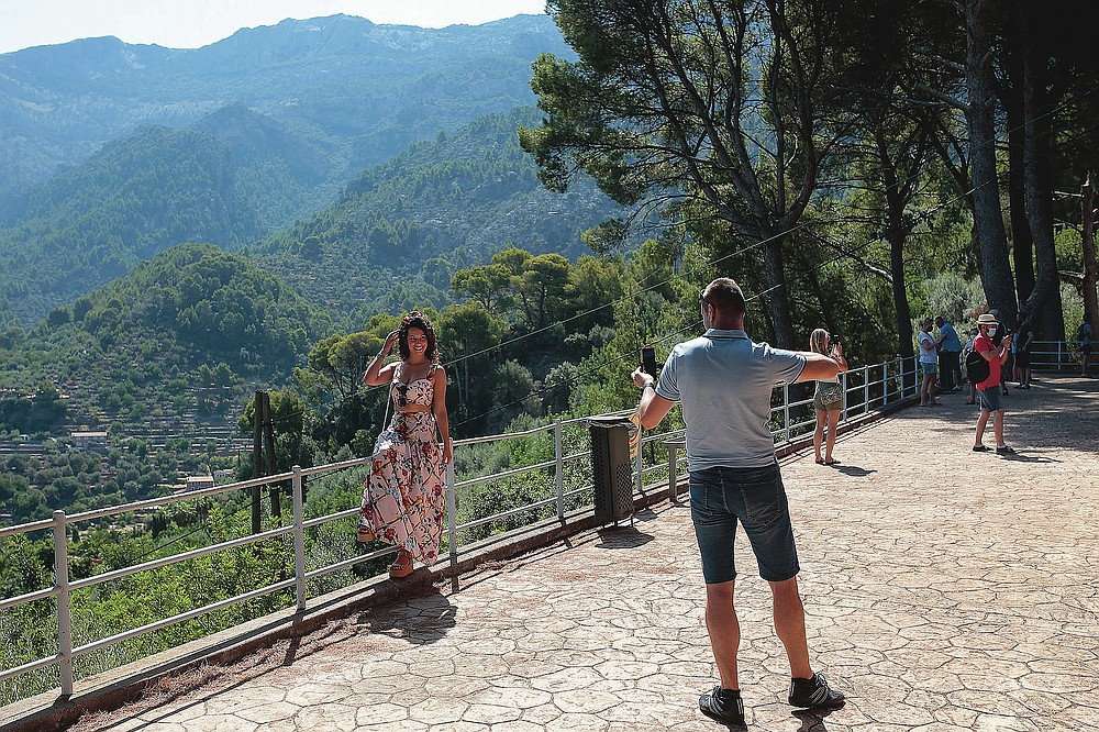 Tourists take photos in town of Sóller in the Balearic Island of Mallorca, Spain, Monday, July 27, 2020. Britain has put Spain back on its unsafe list and announced Saturday that travelers arriving in the U.K. from Spain must now quarantine for 14 days. (AP Photo/Joan Mateu)