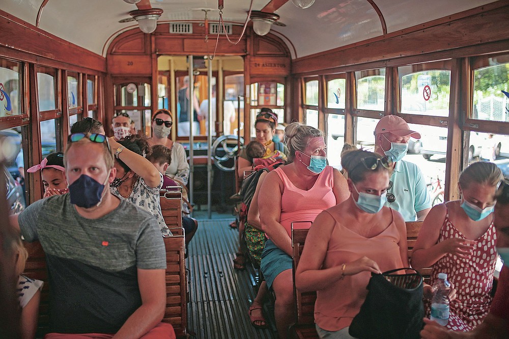 Tourists and locals ride a tram in town of Sóller in the Balearic Island of Mallorca, Spain, Monday, July 27, 2020. Britain has put Spain back on its unsafe list and announced Saturday that travelers arriving in the U.K. from Spain must now quarantine for 14 days. (AP Photo/Joan Mateu)