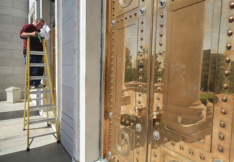 Arkansas Secretary of State employee Richard Adcock whips his forehead as he works Tuesday July 28, 2020 in Little Rock polishing the bronze doors on the front of the Arkansas State Capitol. (Arkansas Democrat-Gazette/Staton Breidenthal)