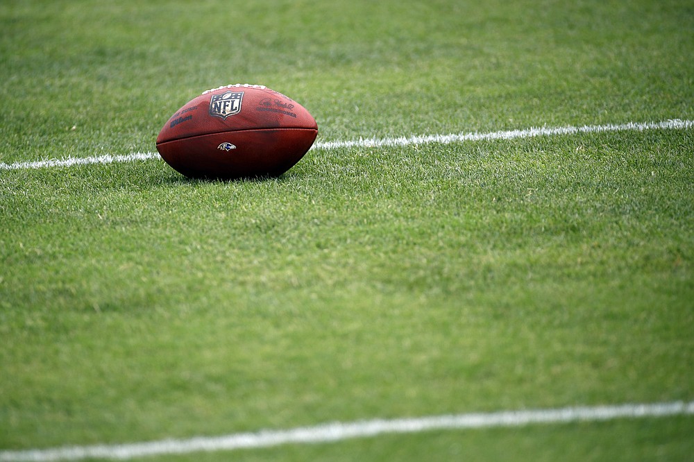 FILE - In this July 28, 2017, file photo, a football sits on a Baltimore Ravens practice field during NFL football training camp in Owings Mills, Md. As teams adhere to the medical protocols that wisely and necessarily have been ordered by the league and the players’ union, any sort of football action might be delayed until mid-August. (AP Photo/Patrick Semansky, File)