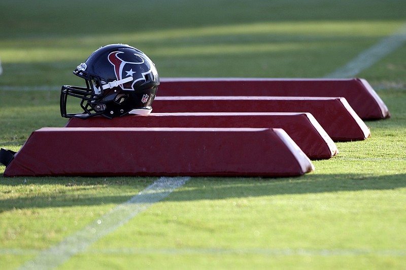 FILE - In this Aug. 3, 2010, file photo, a Houston Texans helmet sits on pads during NFL football training camp in Houston. As teams adhere to the medical protocols that wisely and necessarily have been ordered by the league and the players’ union, any sort of football action might be delayed until mid-August. (AP Photo/David J. Phillip, File) story.lead_photo.caption