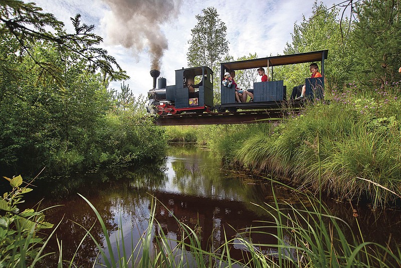 A miniature steam train runs across a bridge on Pavel Chilin's personal railway in Ulyanovka village outside St. Petersburg, Russia Sunday, July 19, 2020. It took Chilin more than 10 years to build a 350-meter-long mini-railway twisting through the grounds of his cottage home about 50 kilometers (some 30 miles) outside St. Petersburg, complete with various branches, dead ends, circuit loops, and even three bridges.(AP Photo/Dmitri Lovetsky)