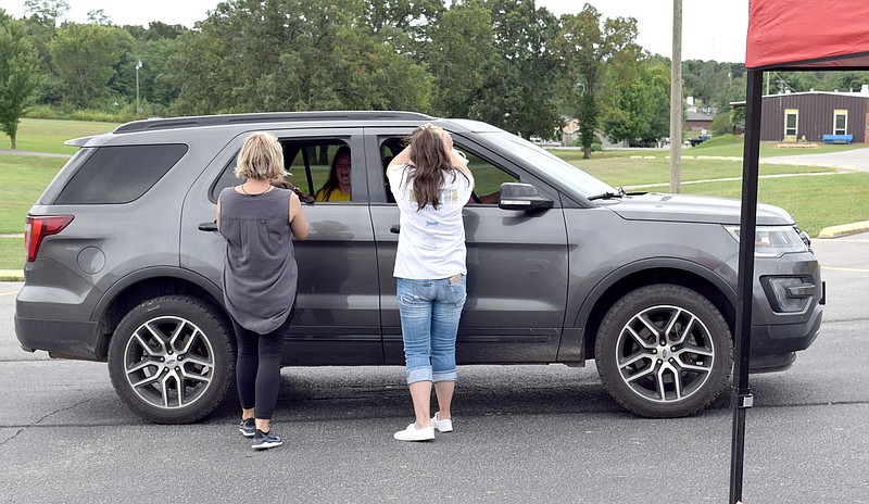 Westside Eagle Observer/MIKE ECKELS

Rachel Gibson (left) and Sandy Duncan help distribute food, books and games to a Decatur family July 27 during the final Food and Fun Pack Giveaway at Decatur High School. The Food and Fun Pack drive replaced the normal Seamless Summer food program which was shut down due to the covid-19 school shutdown this year.