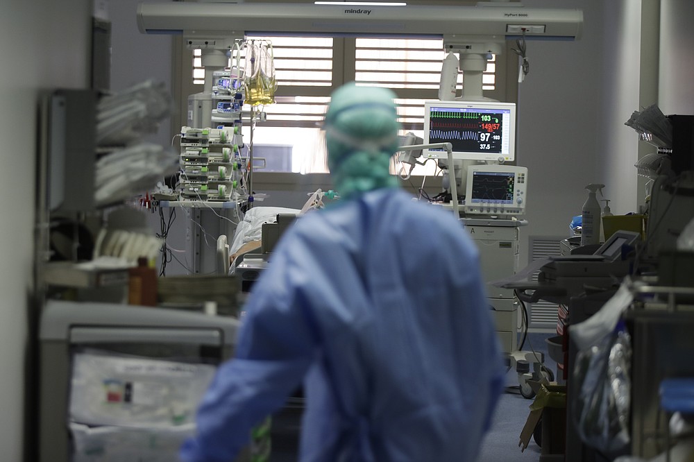 FILE - In this Monday, March 16, 2020 file photo, a doctor watches a coronavirus patient under treatment in the intensive care unit of the Brescia hospital, Italy. Amid the chaos of the pandemic’s early days, doctors who faced the first COVID-19 onslaught reached across oceans and language barriers in an unprecedented effort to advise colleagues trying to save lives. (AP Photo/Luca Bruno)