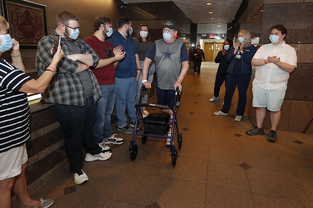 COVID-19 patient Stephen Donelson is applauded by family and health care professionals as he departs the Zale Hospital on the UT Southwestern Campus in Dallas, Friday, June 19, 2020. During his three-month hospital stay, Donelson spent 17 days on a ventilator. When it was removed, he was too weak to even sit without support and the breathing tube had taken away his ability to swallow. (AP Photo/Tony Gutierrez)