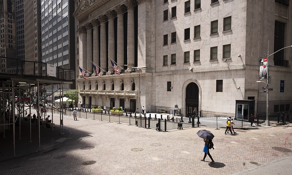 People pass the New York Stock Exchange, Thursday, July 30, 2020. Stocks are falling on Wall Street Thursday after reports showed that layoffs are continuing at a stubborn pace and that the U.S. economy contracted at a nearly 33% annual rate in the spring. (AP Photo/Mark Lennihan)