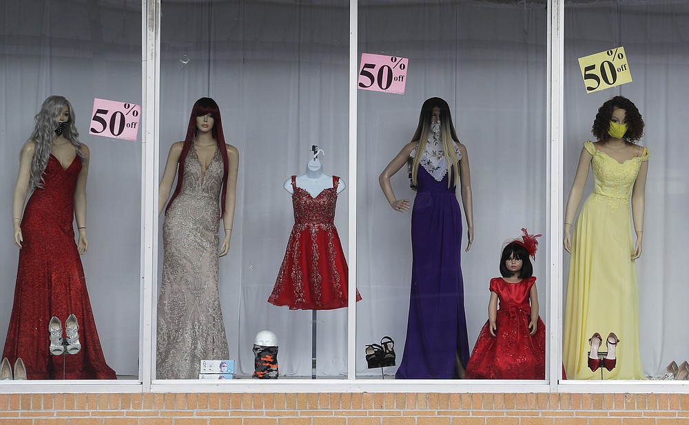 Sale signs are posted on a display window with mask covered mannequins at a dress shop, Thursday, July 30, 2020, in McAllen,Texas. (AP Photo/Eric Gay)
