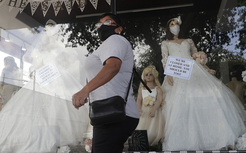 A shopper passes a display window with mask covered mannequins at a dress store, Thursday, in McAllen, Texas. - AP Photo/Eric Gay