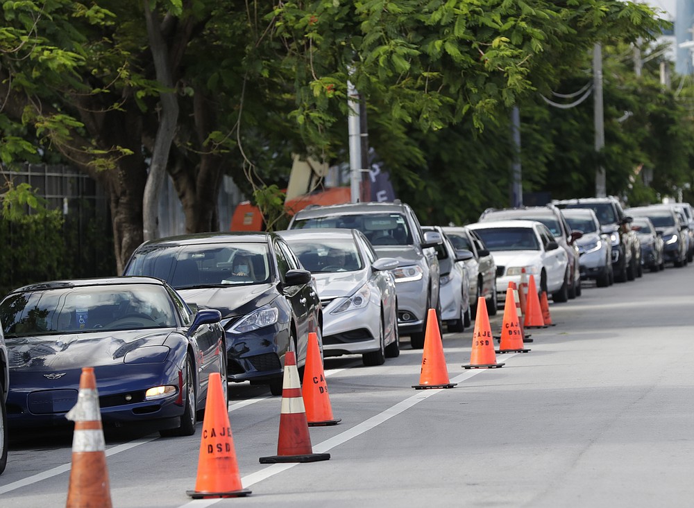 A line of cars wait at the entrance to a kosher food drive-thru distribution site, Wednesday, July 29, 2020, at the Greater Miami Jewish Federation building in Miami. (AP Photo/Wilfredo Lee)
