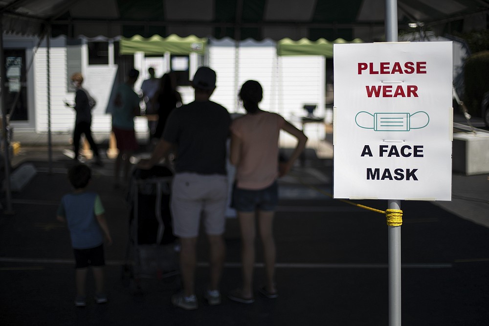 Customers with masks line up at a Brickley's Ice Cream shop, one of two stores, in Narragansett, R.I., Wednesday, July 29, 2020. The other nearby location closed when teenage workers were harassed by customers who refused to wear a mask or socially distance. Disputes over masks and mask mandates are playing out at businesses, on public transportation and in public places across America and other nations. (AP Photo/David Goldman)