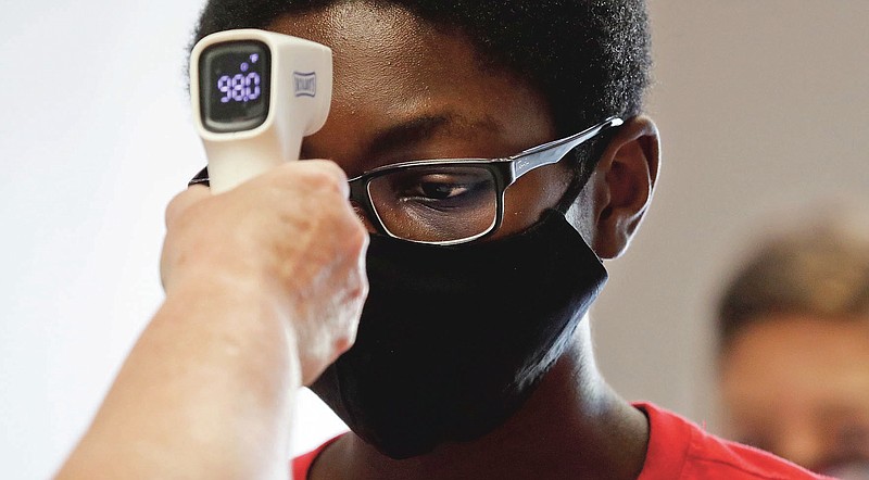 FILE - In this Tuesday, July 14, 2020 file photo, a student wearing a mask has his temperature checked by a teacher before entering a school for summer classes in Texas. On Friday, July 31, 2020, The Associated Press reported on stories circulating online incorrectly asserting that infrared thermometers, which are held near the forehead to scan body temperature without direct contact, point an infrared light directly at the brain’s pineal gland, exposing it to harmful radiation. Infrared thermometers don’t emit radiation into the brain; they sense heat emitted by the body. They pose no risk to the pineal gland, which is located deep within the brain, according to Dr. Haris Sair, director of neuroradiology at Johns Hopkins University. (AP Photo/LM Otero) story.lead_photo.caption