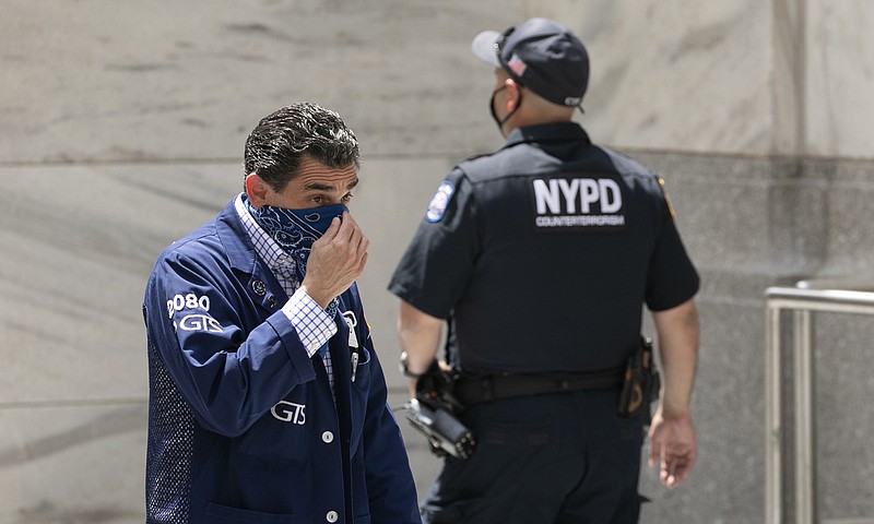 A stock trader, left, adjusts his mask as he enters the New York Stock Exchange, Thursday, July 30, 2020.  Strong gains for Big Tech stocks are helping to prop up Wall Street in early Friday trading following blowout profit reports from some of the market’s most influential companies.  (AP Photo/Mark Lennihan)