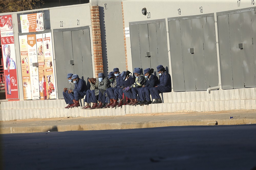 Zimbabwean police take a break at the side of a street in Harare, Friday, July, 31, 2020. Zimbabwe's capital, Harare, was deserted Friday, as security agents vigorously enforced the country's lockdown amidst planned protests. Police and soldiers manned checkpoints and ordered people seeking to get into the city for work and other chores to return home. (AP Photo/Tsvangirayi Mukwazhi)