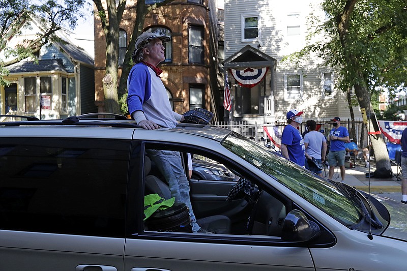 Chicago Cubs fans wait for a ball outside of Wrigley Field before the July 24 Opening Day game between the Chicago Cubs and the Milwaukee Brewers in Chicago. In a normal year, that would mean a sellout crowd at Wrigley Field and jammed bars surrounding the famed ballpark. But in a pandemic-shortened season, it figures to be a different atmosphere. - Photo by Nam Y. Huh of The Associated Press story.lead_photo.caption