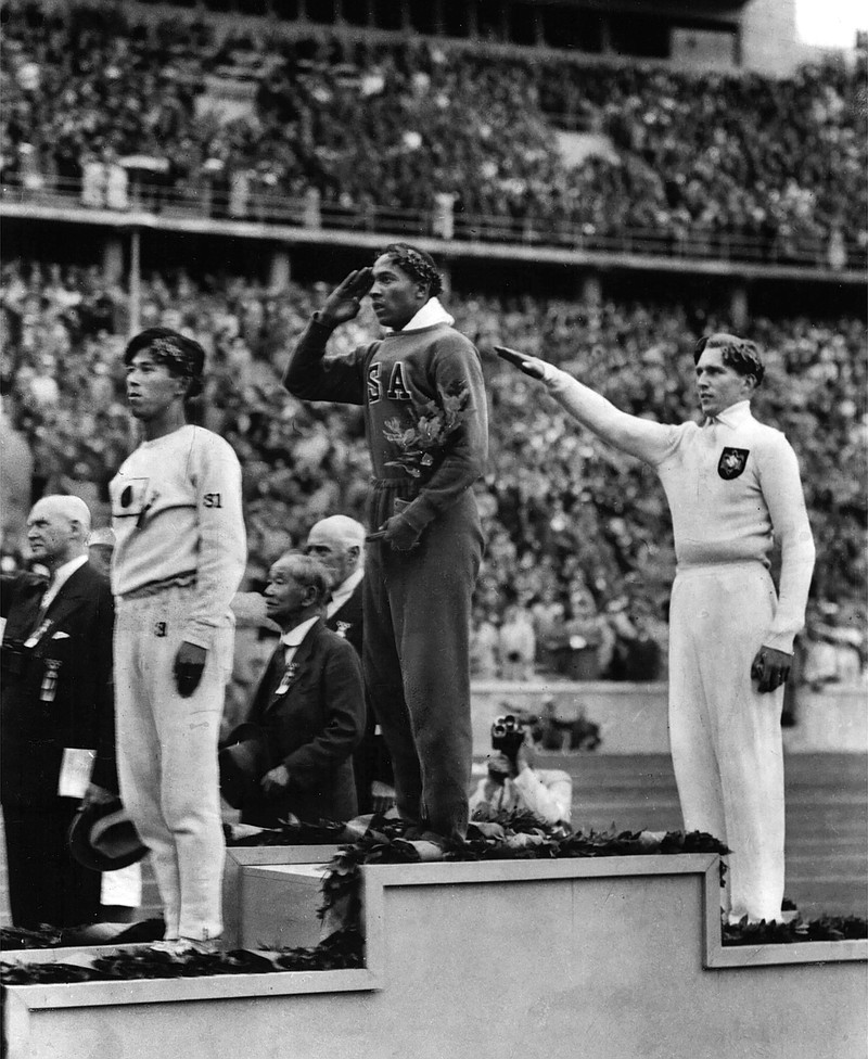America's Jesse Owens, center, salutes during the presentation of his gold medal for the long jump on Aug. 11, 1936, after defeating Nazi Germany's Lutz Long, right, during the 1936 Summer Olympics in Berlin. Naoto Tajima of Japan, left, placed third. The performance of Jesse Owens will be honored in the stadium where he won four gold medals at the 1936 Olympic Games when the world championships are held in Berlin this month. - The Associated Press file photo