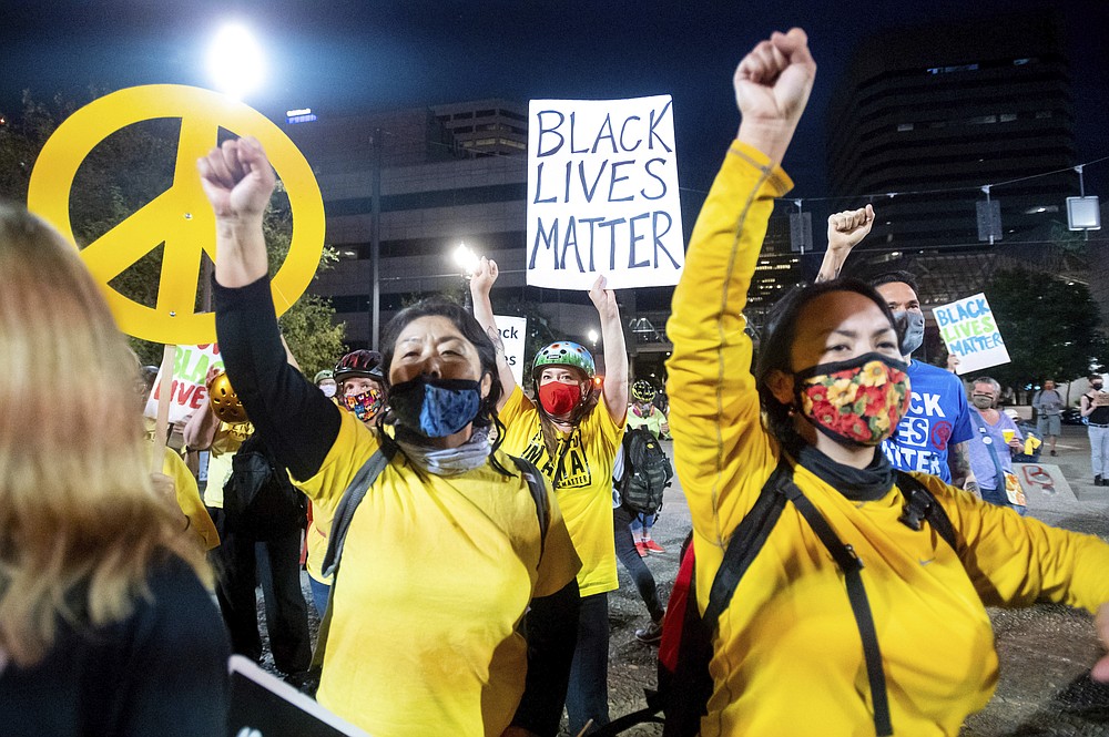 Krista Swan, part of Moms United for Black Lives, holds a Black Lives Matter sign while protesting on Friday, July 31, 2020, in Portland, Ore. Following an agreement between Democratic Gov. Kate Brown and the Trump administration to reduce federal officers in the city, the protest remained largely peaceful without major confrontations between demonstrators and officers. (AP Photo/Noah Berger)
