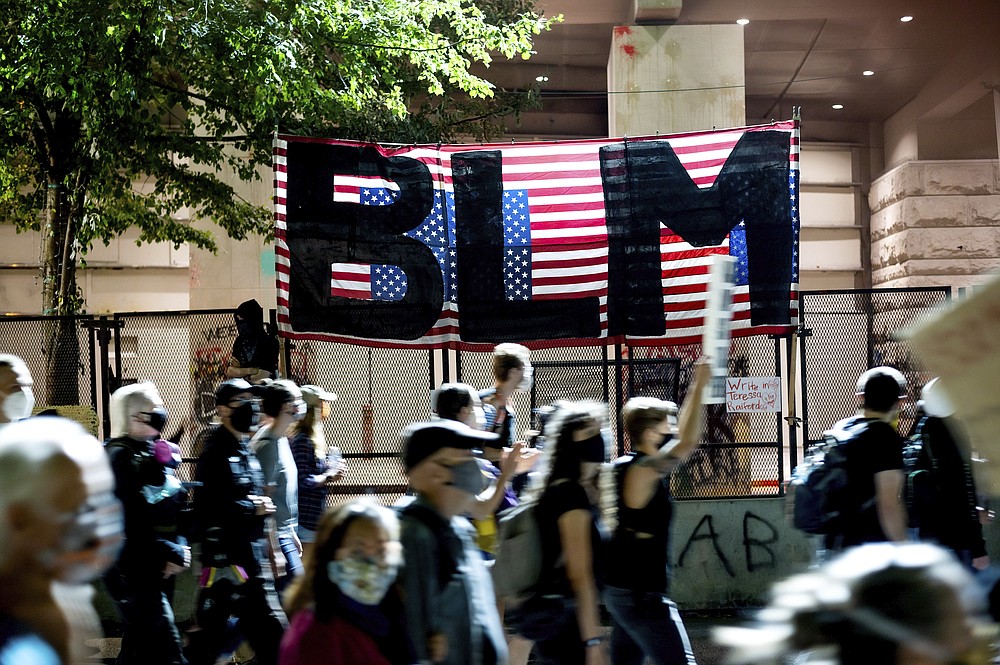 Black Lives Matter protesters march past the Mark O. Hatfield United States Courthouse on Friday, July 31, 2020, in Portland, Ore. Following an agreement between Democratic Gov. Kate Brown and the Trump administration to reduce federal officers in the city, nightly protests remained largely peaceful without major confrontations between demonstrators and officers. (AP Photo/Noah Berger)
