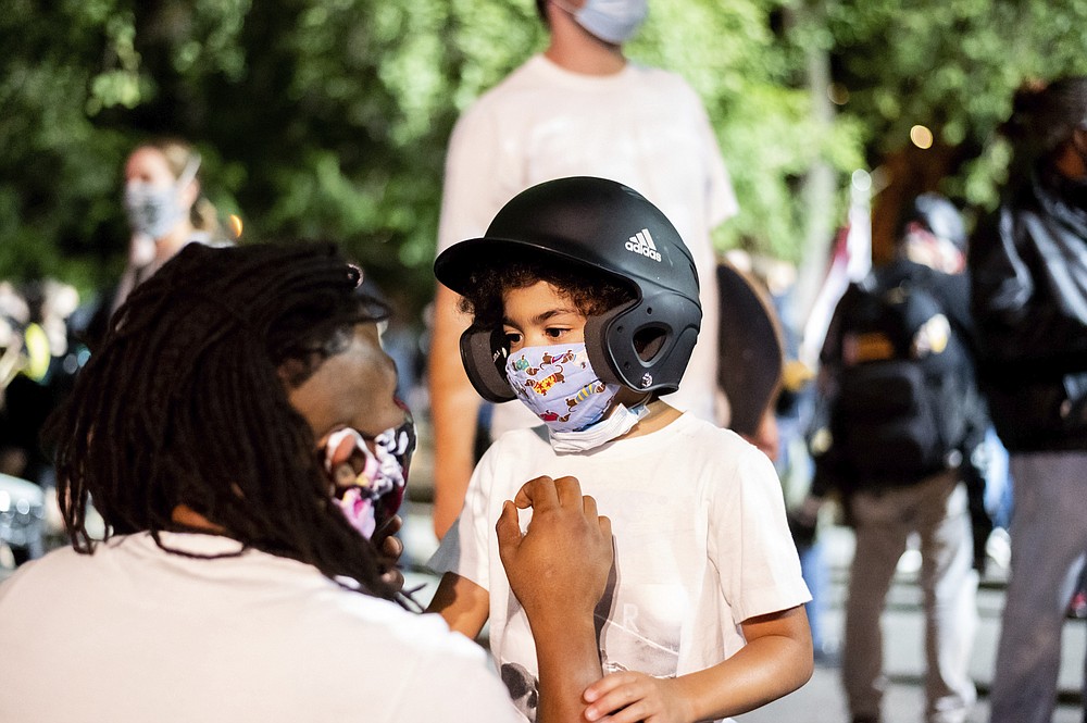 Leshan Terry speaks with his son Leshan Terry, Jr., 6, during a Black Lives Matter protest at the Mark O. Hatfield United States Courthouse on Friday, July 31, 2020, in Portland, Ore. Following an agreement between Democratic Gov. Kate Brown and the Trump administration to reduce federal officers in the city, nightly protests remained largely peaceful without major confrontations between demonstrators and officers. (AP Photo/Noah Berger)