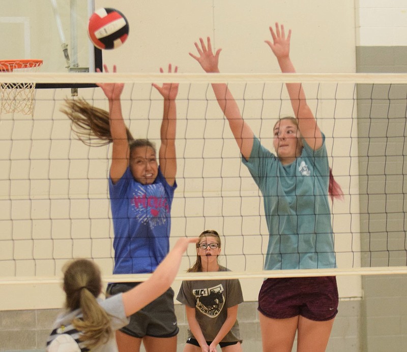 RICK PECK/SPECIAL TO MCDONALD COUNTY PRESS Kaycee Factor (left) and Sydnie Sanny attempt to block a spike during the McDonald County High School volleyball team's recent practice.