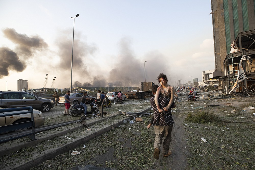 People evacuate wounded after of a massive explosion in Beirut, Lebanon, Tuesday, Aug. 4, 2020. Massive explosions rocked downtown Beirut on Tuesday, flattening much of the port, damaging buildings and blowing out windows and doors as a giant mushroom cloud rose above the capital. Witnesses saw many people injured by flying glass and debris. (AP Photo/Hassan Ammar)