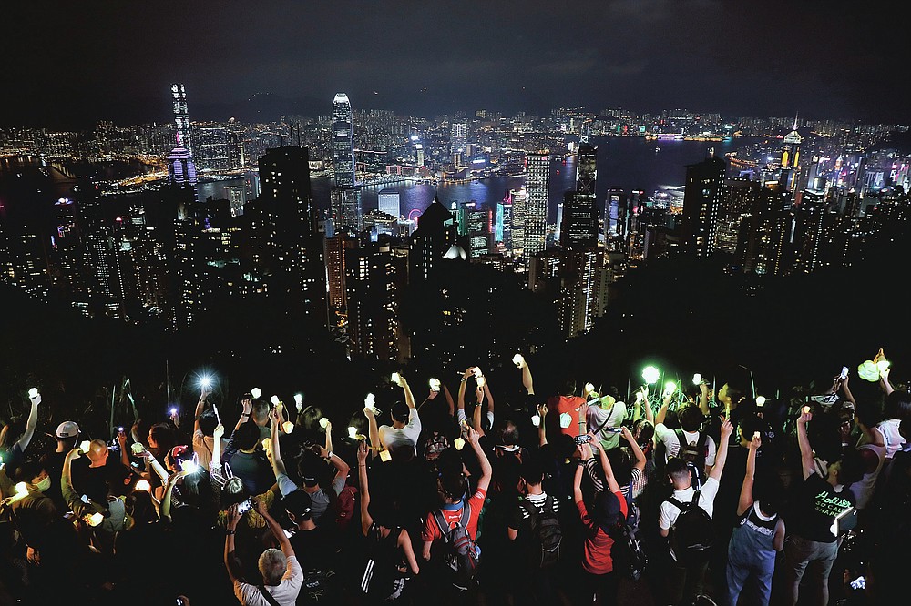 FILE - In this Friday, Sept. 13, 2019 file photo, demonstrators hold up the mobile phone lights as they form a human chain at the Peak, a tourist spot in Hong Kong. Hong Kong has a long tradition of public demonstrations dating from its days as a British colony. However, protest activity has been tamped down since Beijing enacted a sweeping security law in June 2020, banning speech seen as promoting secession. (AP Photo/Kin Cheung)