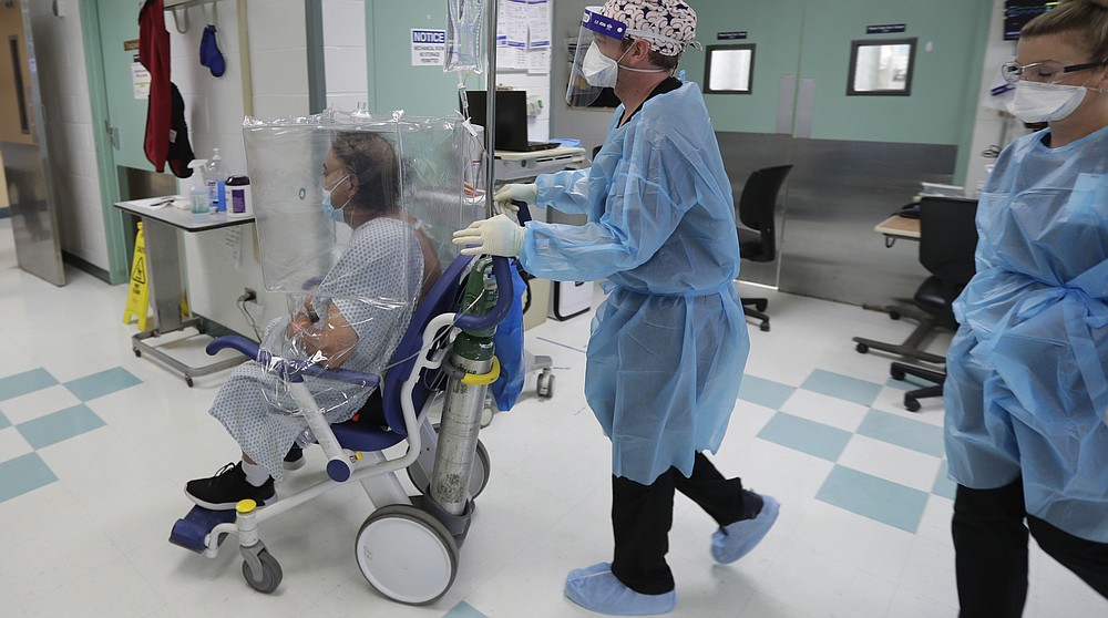 A man with COVID-19, wearing a protective cover, is transferred from the emergency room to a COVID-19 unit at Starr County Memorial Hospital, Monday, July 27, 2020, in Rio Grande City, Texas. For nearly a month, the Rio Grande Valley pleaded for a field hospital, but not until Monday was one ready. (AP Photo/Eric Gay)