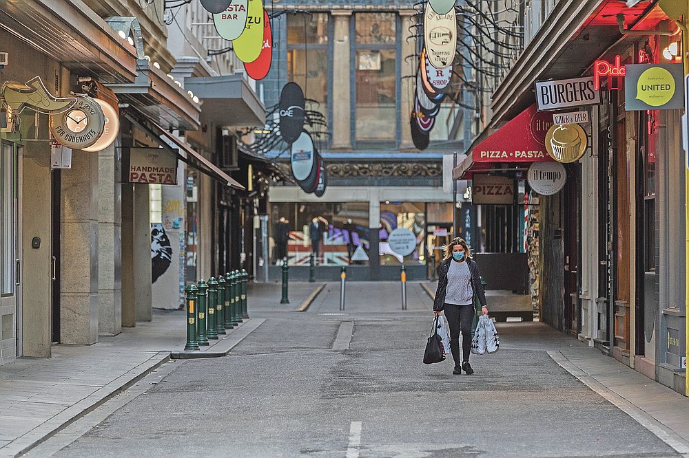A lone shopper walks down the usually busy Degraves Street laneway fame for its cafe's and coffee during lockdown in Melbourne, Australia, Wednesday, Aug. 5, 2020. Victoria state, Australia's coronavirus hot spot, announced on Monday that businesses will be closed and scaled down in a bid to curb the spread of the virus. (AP Photo/Asanka Brendon Ratnayake)
