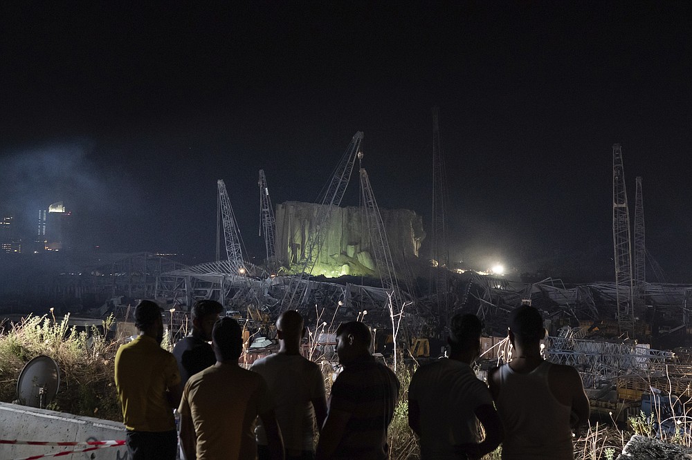 People look at the scene of Tuesday's explosion that hit the seaport of Beirut, Lebanon, Friday, Aug. 7, 2020. Rescue teams were still searching the rubble of Beirut's port for bodies on Friday, nearly three days after a massive explosion sent a wave of destruction through Lebanon's capital, killing over a hundred people and wounding thousands. (AP Photo/Felipe Dana)