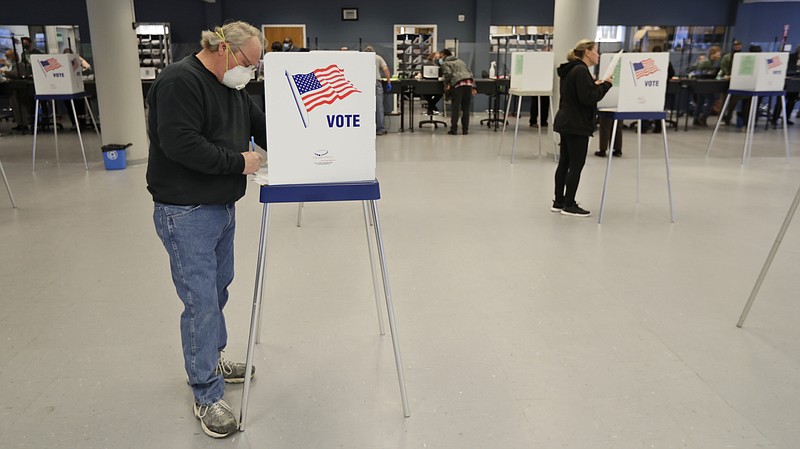 This Tuesday, April 28, 2020 file photo shows Jerome Fedor, left, voting using social distancing at the Cuyahoga County Board of Elections, in Cleveland, Ohio. Ohio's elections chief says his office plans to remove about 120,000 inactive Ohio voter registrations from state voter rolls after the November election. (AP Photo/Tony Dejak, File) story.lead_photo.caption