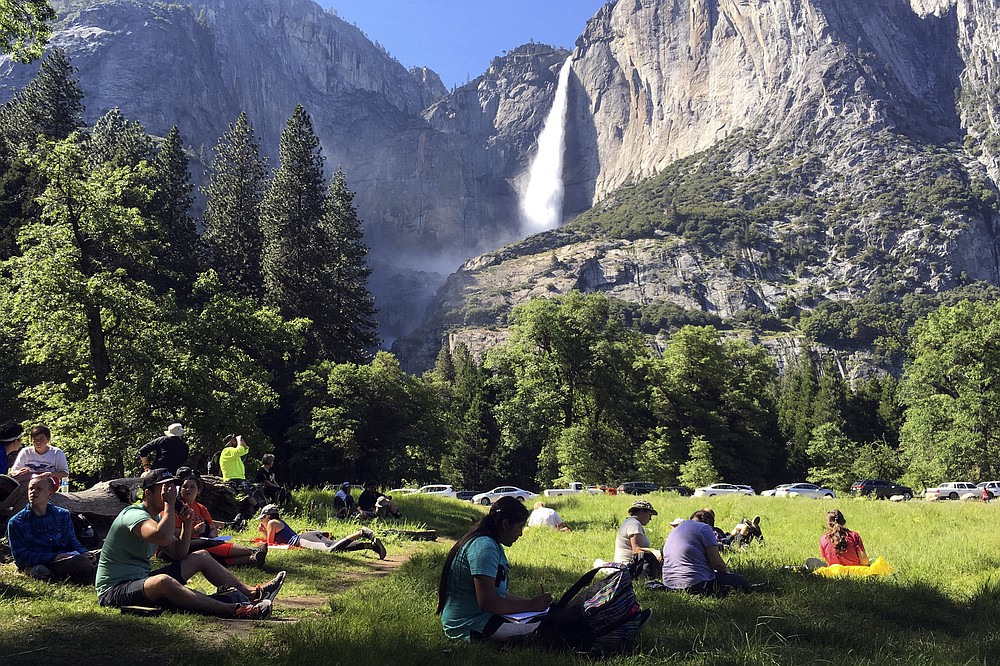 FILE - In this May 25, 2017 file photo, a class of eighth-grade students and their chaperones sit in a meadow at Yosemite National Park, Calif., below Yosemite Falls. Interior Secretary David Bernhardt announced the surprise replacement Friday, Aug. 7, 2020, of the 30-year parks veteran running the National Park Service, naming one of his advisers, Margaret Everson, to run the agency instead as it begins to help divvy up a new, multibillion-dollar annual bequest from Congress. (AP Photo/Scott Smith, File)