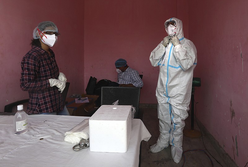 A health worker gears up to take nasal swab samples for COVID- 19 testing through rapid antigen methodology, in New Delhi, India , Friday, Aug. 7, 2020. As India hit another grim milestone in the coronavirus pandemic on Friday, crossing 2 million cases and more than 41,000 deaths, community health volunteers went on strike complaining they were ill-equipped to respond to the wave of infection in rural areas. (AP Photo/Manish Swarup)