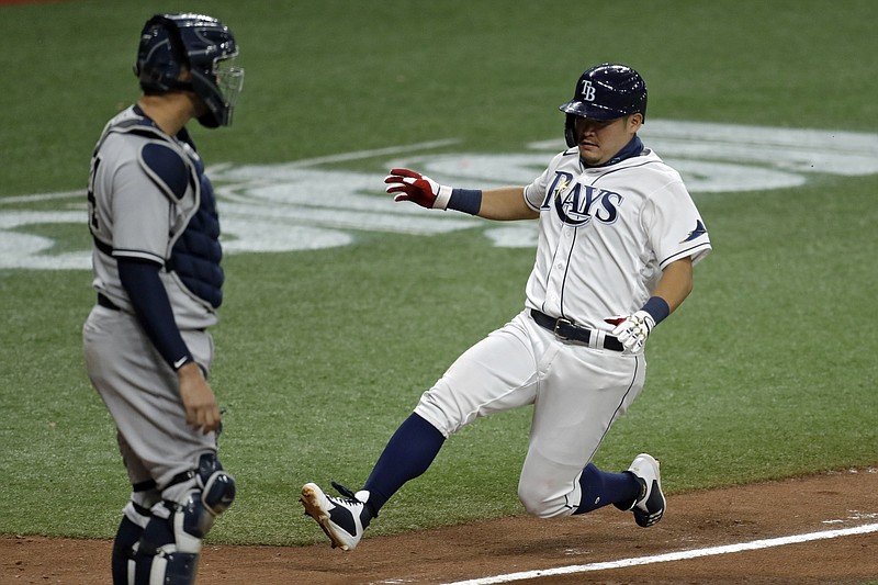 Tampa Bay Rays' Yoshi Tsutsugo, of Japan, right, scores in front of New York Yankees catcher Gary Sanchez on a sacrifice fly by Michael Perez off Yankees pitcher Adam Ottavino during the eighth inning of Friday's game in St. Petersburg, Fla. - Photo by Chris O'Meara of The Associated Press