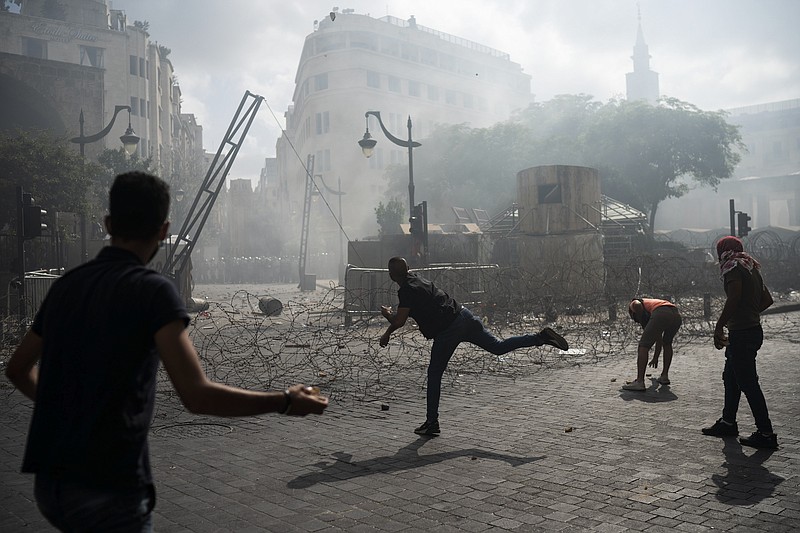 People clash with police during a protest against the political elites and the government after this week's deadly explosion at Beirut port which devastated large parts of the capital and killed more than 150 people, in Beirut, Lebanon, Saturday, Aug. 8, 2020. (AP Photo/Felipe Dana)