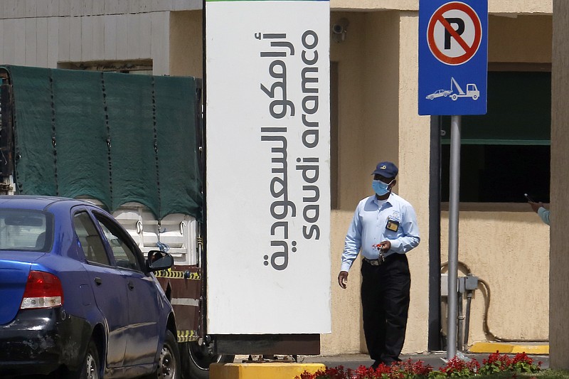 In this March 9 file photo, a security person wears a mask as he checks vehicles entering a compound for Saudi Aramco in Jiddah, Saudi Arabia. Saudi Aramco's net income plunged by 50% in the first half of the year, according to figures published Sunday, offering a revealing glimpse into the impact of the coronavirus pandemic on one of the world's biggest oil producers. - AP Photo/Amr Nabil