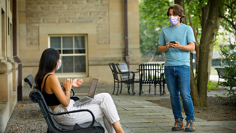 In this photo provided by Jason Koski and Cornell University, Bryan Maley, right, a grad student in the Master of Public Health program, interviews a student on campus about mask-wearing experiences as part of a public health survey,  July 30, in Ithaca, N.Y. - Jason Koski/Cornell University via AP