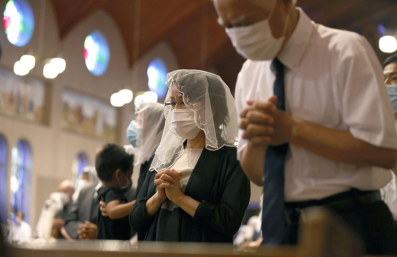 Christians, wearing face masks, pray for the victims of U.S. atomic bombing during a mass at Urakami Cathedral in Nagasaki, southern Japan, Sunday, Aug. 9, 2020. Nagasaki marked the 75th anniversary of the atomic bombing on Sunday. (Kyodo News via AP)