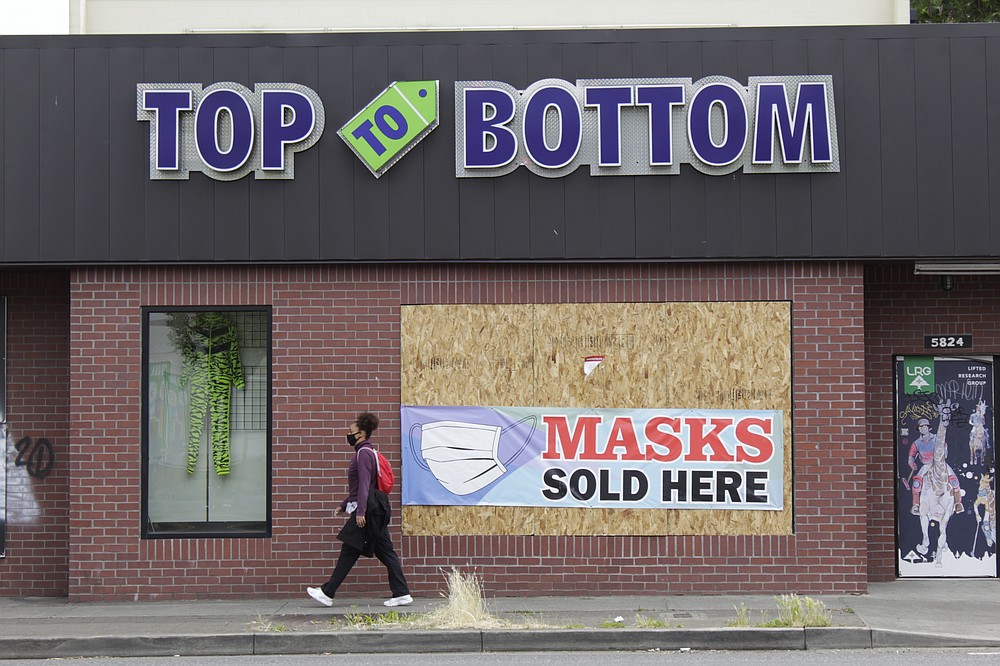 FILE - In this July 1, 2020, file photo, a woman walks past a business damaged during recent protests in North Portland, a historically Black neighborhood in Oregon. Protests in Portland, Oregon have topped the headlines for days, but lost in the shouting are the voices of Black Portlanders themselves and their feelings about the unrest are nuanced and diverse. (AP Photo/Gillian Flaccus, File)